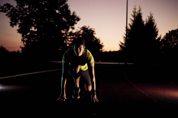 istock Young male runner is ready to get start running in the evening after sunset, young man runner looking forward to run 1006721872