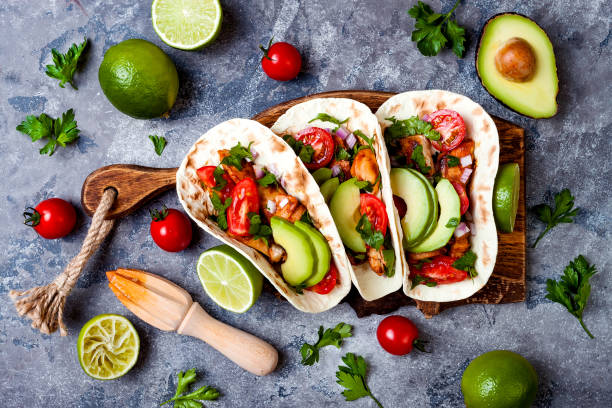 istock Mexican grilled chicken tacos with avocado, tomato, onion on rustic stone table. Recipe for Cinco de Mayo party. Top view, overhead, flat lay. 1006733642