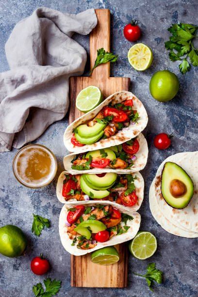 istock Mexican grilled chicken tacos with avocado, tomato, onion on rustic stone table. Recipe for Cinco de Mayo party. Top view, overhead, flat lay. 1006733662