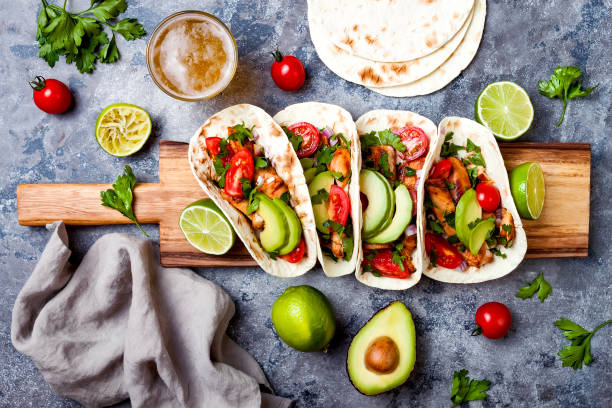 istock Mexican grilled chicken tacos with avocado, tomato, onion on rustic stone table. Recipe for Cinco de Mayo party. Top view, overhead, flat lay. 1006733696