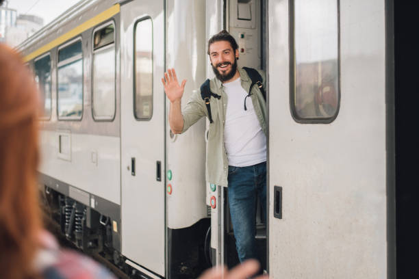 istock Joyful young man exiting the train and waving his hand 1006733836