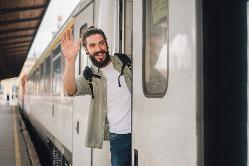 Man peeking from train and waving his hand