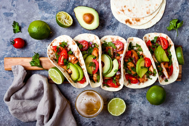istock Mexican grilled chicken tacos with avocado, tomato, onion on rustic stone table. Recipe for Cinco de Mayo party. Top view, overhead, flat lay. 1006734050