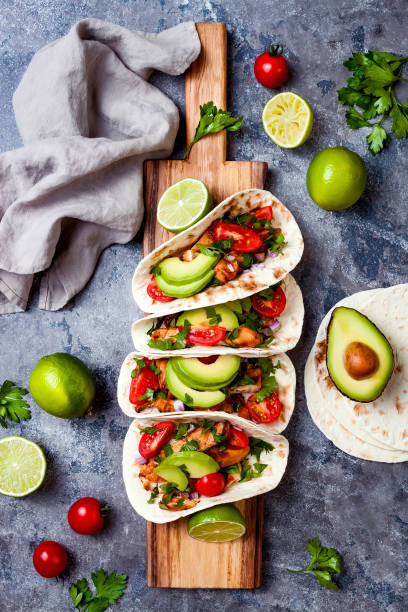 istock Mexican grilled chicken tacos with avocado, tomato, onion on rustic stone table. Recipe for Cinco de Mayo party. Top view, overhead, flat lay. 1006734136