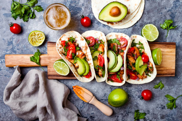 istock Mexican grilled chicken tacos with avocado, tomato, onion on rustic stone table. Recipe for Cinco de Mayo party. Top view, overhead, flat lay. 1006734172