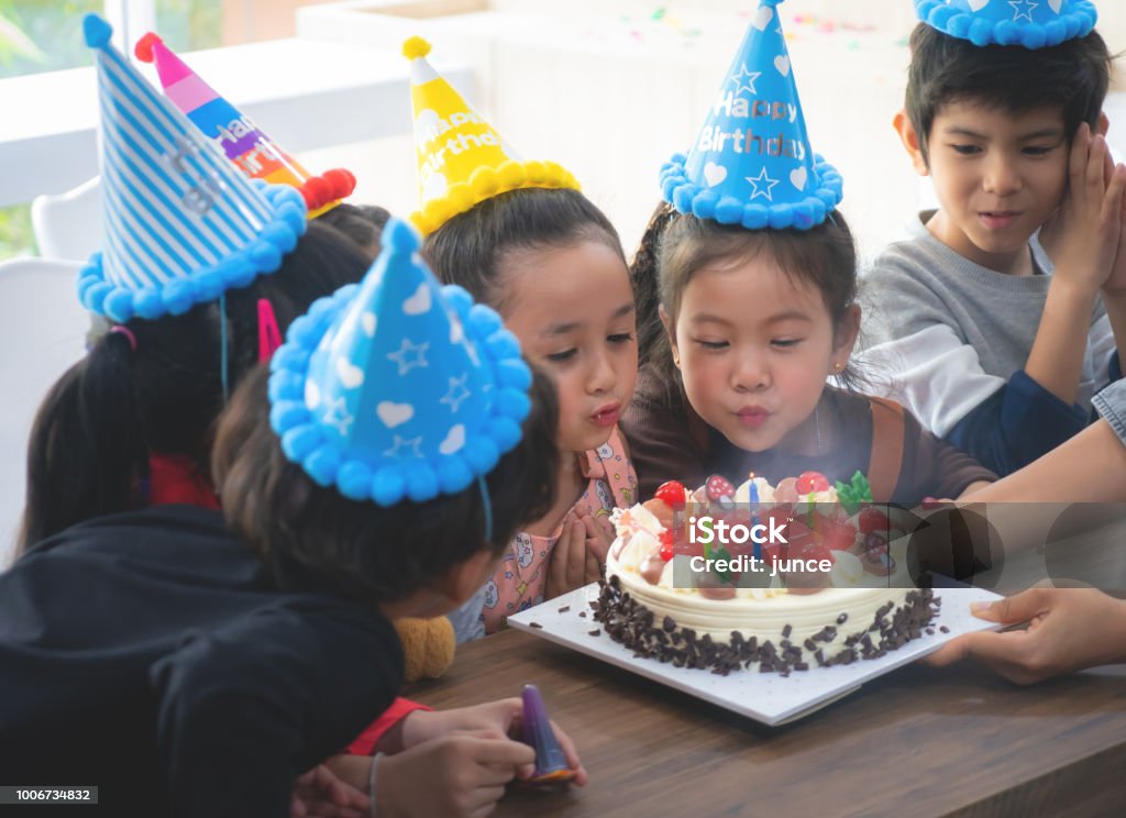 Gruppo di amici bambini sta soffiando torta di compleanno - Foto stock royalty-free di Compleanno