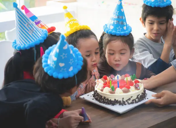 Photo of Group of kid friends is blowing birthday cake