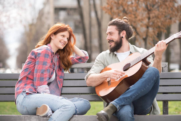 istock Young couple with acoustic guitar looking at each other 1006738996