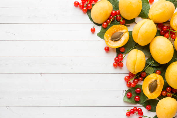 istock Fresh apricot and red currant berries with leaves on a light table. 1006750632