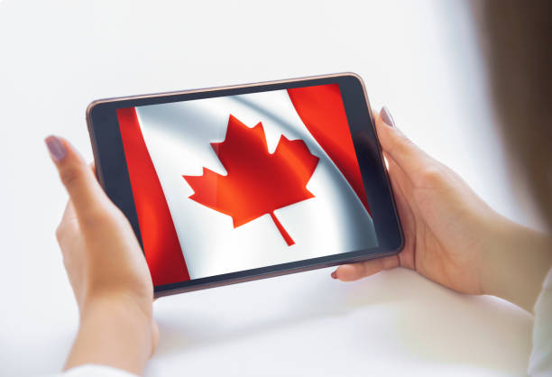 istock The young woman is using a tablet. Country flags visuals on screen. Canada Flag. 1006759198