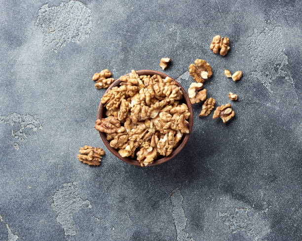 istock Walnut kernels on gray background with copy space. Nuts in clay bowl. Top view. 1006771360