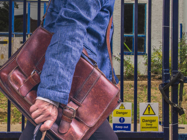 Businesswomen with leather briefcase walking along a city street A man with a leather briefcase and a blue jacket walking along the warning signs. For Business uncompromising stock pictures, royalty-free photos & images