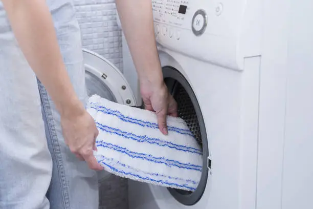 Photo of Washing head of cleaning mop in washer after cleaning house