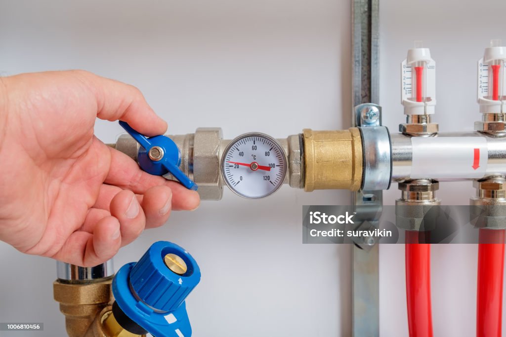 The men's hand opens the ball valve on the collector The men's hand opens the ball valve on the collector for warm floor Water Stock Photo