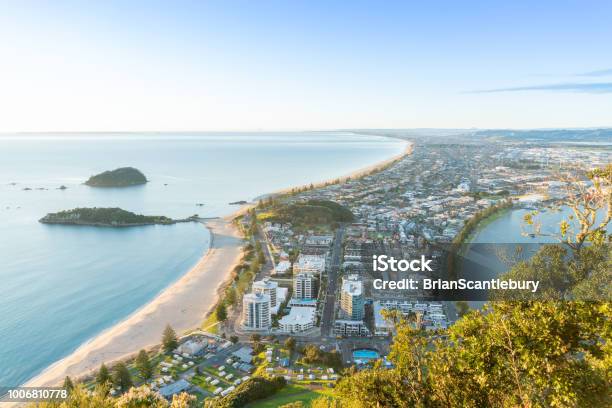 Mount Maunganui Stretches Out Below As Sun Rises On Horizon And Falls Across Ocean Beach And Buildings Stock Photo - Download Image Now