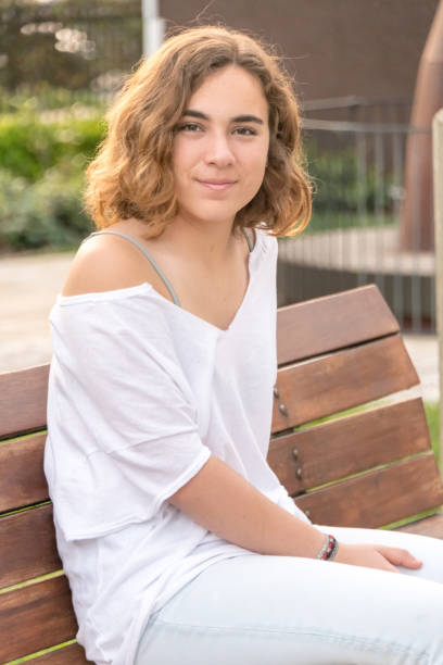istock Smiling young woman sitting in a park bench 1006820802