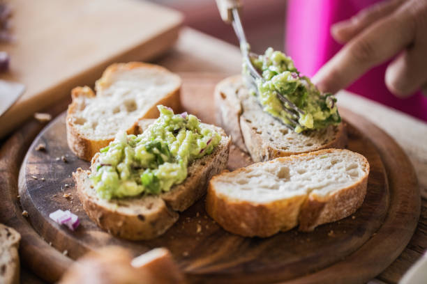 istock Sandwich making -avocado guacamole at fresh bread slices, close-up 1006837778