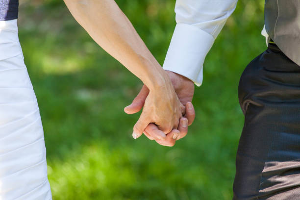 istock Cropped Image Of Bride And Bridegroom Holding Hands On Field 1006859006