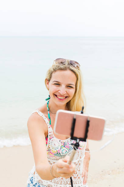 istock Cheerful Woman Taking Selfie While Standing At Beach 1006865538