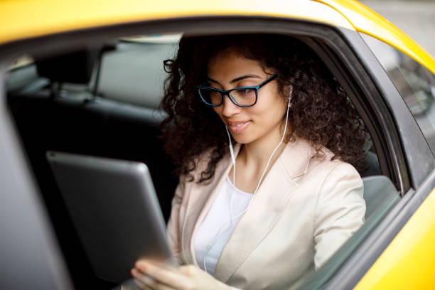 istock Young businesswoman using digital tablet in a taxi 1006875922