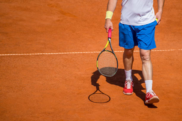 istock Low Section Of Man With Racket Walking At Playing Field 1006892632