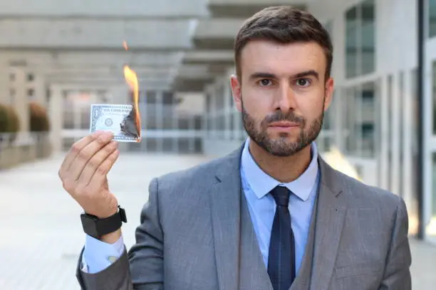 Photo of Serious businessman burning dollar bill