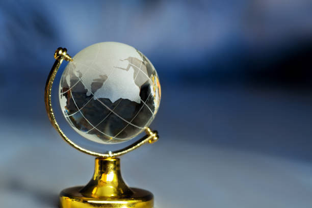 istock Glass globe on a stand on a blue background with rays. Planet earth globe with continents figurine on table 1006913716