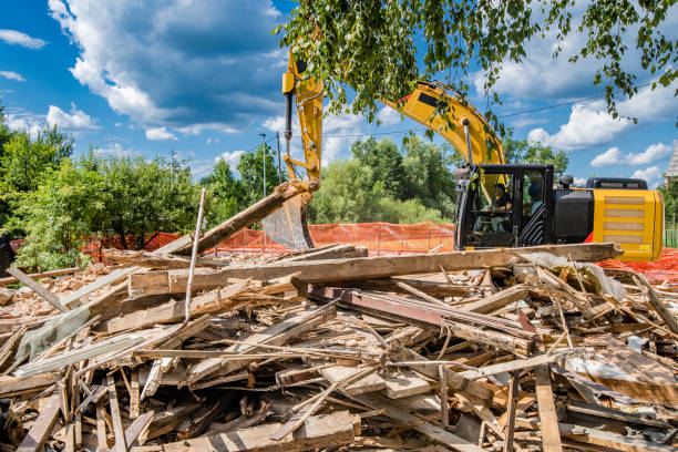 Side view of an excavator digging through rubble at a demolition site.