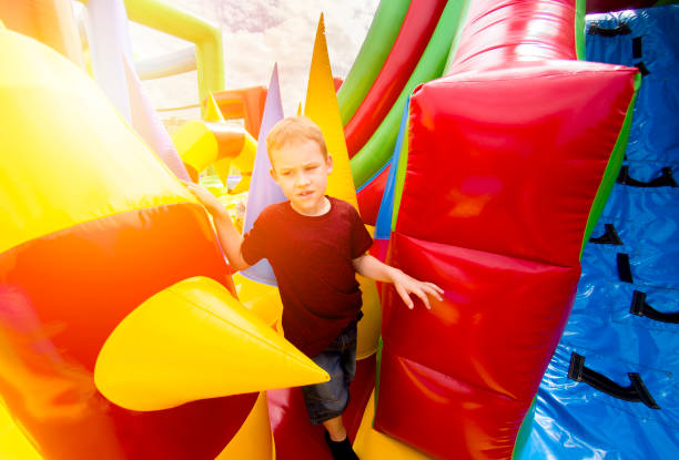 Child jumping on colorful playground trampoline. Kids jump in inflatable bounce castle on kindergarten birthday party Activity and play center for young child. Little girl playing outdoors in summer. niño saltando en el trampolín de la colorida zona de juegos. niños saltan en el castillo inflable de la despedida en la fiesta de cumpleaños del jardín de la infancia actividad y jugar el centro para el niño. niña jugando al aire libre en verano.