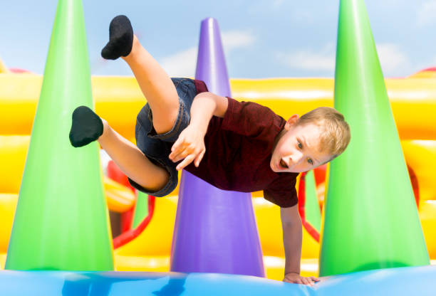 Child jumping on colorful playground trampoline. Kids jump in inflatable bounce castle on kindergarten birthday party Activity and play center for young child. Little girl playing outdoors in summer. niño saltando en el trampolín de la colorida zona de juegos. niños saltan en el castillo inflable de la despedida en la fiesta de cumpleaños del jardín de la infancia actividad y jugar el centro para el niño. niña jugando al aire libre en verano.