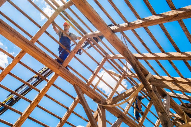 Low angle view of two workers and a crane working on a wooden roof. Blue sky visible in the background.