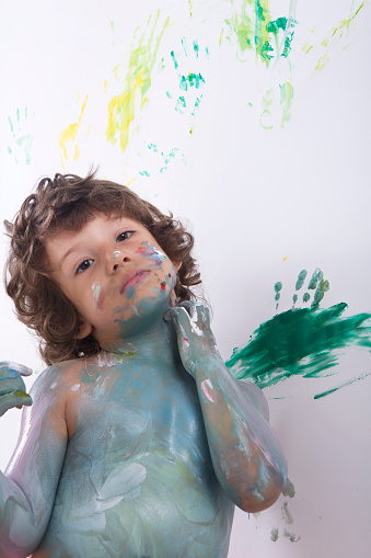 Cute excited boy with hands full of finger paint.Happy Child Finger painting.Creative education.Artwork of children finger .painting on a wall.Happy baby painting with his hands.Creative education ,finger painting.