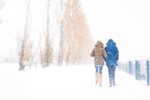 Rear view of couple walking away in snow storm defocused version for enhanced dreamlike quality.