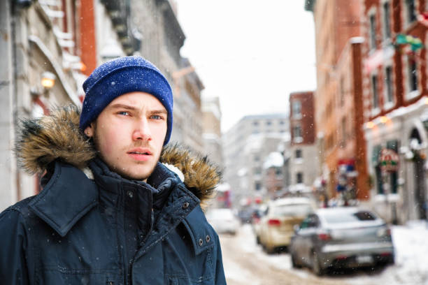 Male Teenager looks away worried during snow storm in Old Montreal Male Teenager looks away worried during snow storm in Old Montreal. toque stock pictures, royalty-free photos & images