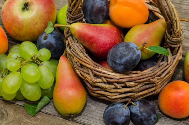 籐のバスケットにフルーツのミックス。素朴な背景にバスケットで健康的な有機果物 - plum fruit basket wicker ストックフォトと画像