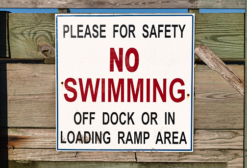 Close view of a no swimming sign on a public pier.