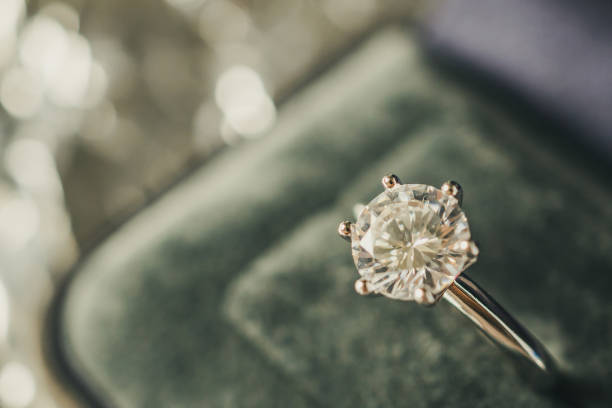 istock luxury engagement Diamond ring in jewelry gift box with bokeh light background 1006940656