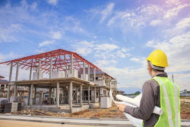 istock Professional engineer architect worker with protective helmet and blueprints paper at house building construction site 1006940932