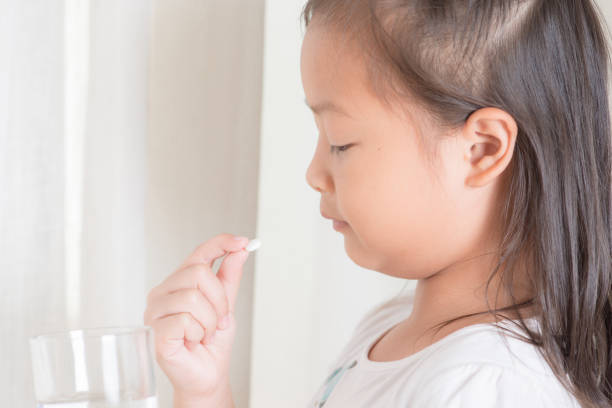 Pharmacy theme, Little asian girl take pill to mouth stock photo