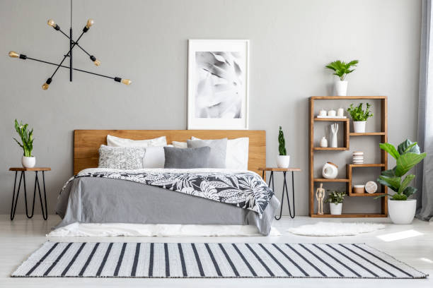 istock Striped carpet near bed with patterned blanket in bedroom interior with poster and plants. Real photo 1006968290