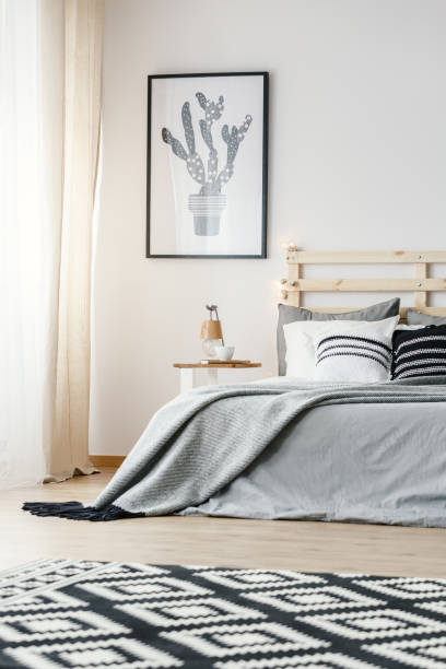 istock Patterned carpet and poster in grey simple bedroom interior with blanket on bed. Real photo 1006968314