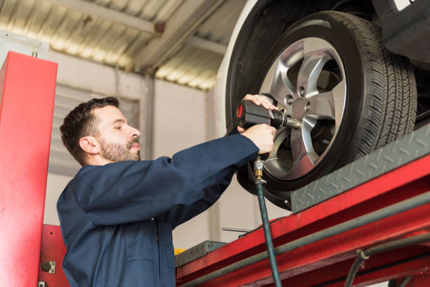 istock Mechanic Servicing Car Tire With Impact Gun In Garage 1006971524