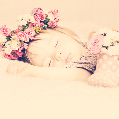 Sweet Little Baby Girl Sleeping in Pink Rose Flowers. Toned Vintage Beauty Background
