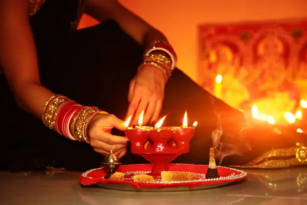 Young woman burning oil lamp on Diwali festival and worshiping of goddess Lakshmi. Diwali or Deepavali is a Hindu festival of lights, originating from the Indian subcontinent, celebrated every year in autumn in the northern hemisphere Diwali is an official holiday in Fiji, Guyana, India.
