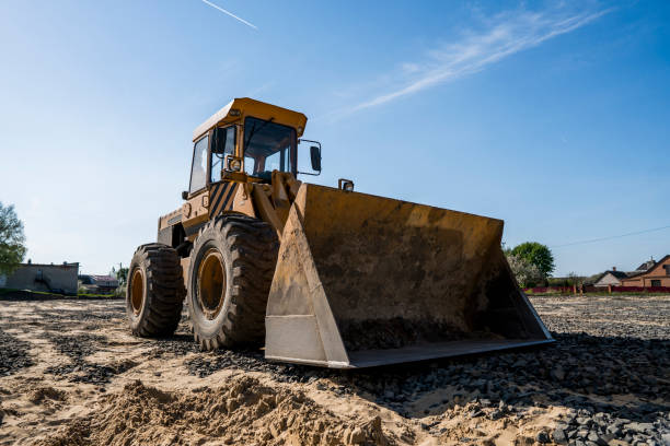 istock Yellow loader with empty bucket stands on a stone gravel during road construction works. The stones for the road. Unloading stone. 1007080290
