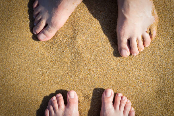 istock Female and male legs on sand, top view 1007083300