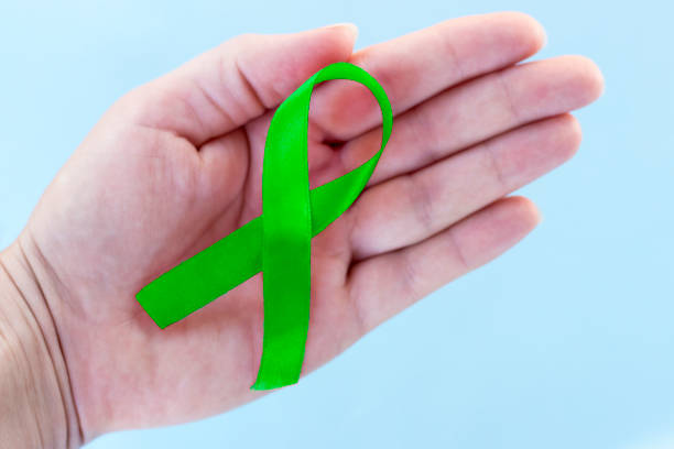 istock Green ribbon on a blue background, close-up, copy space, medical concept 1007083372
