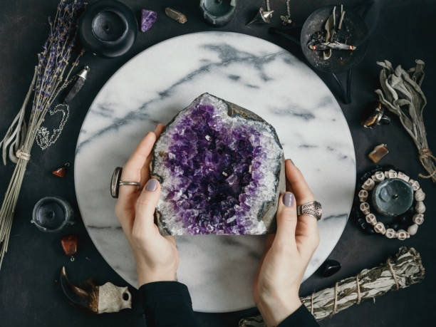 istock The witch is holding amethyst stone surrounded magic things. View from above. 1007083876