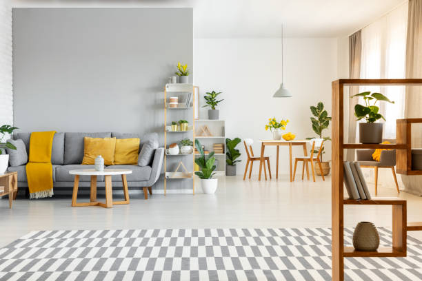 istock Patterned carpet and table in spacious apartment interior with yellow cushions on grey couch. Real photo 1007084502