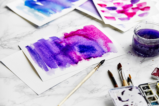 Abstract watercolor composition with ultra violet color dominating. Artist workplace concept, close up, white background.
